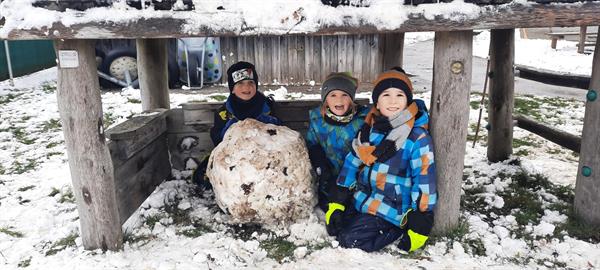 Eine Gruppe von Kindern sitzt im Schnee neben einem Schneemann
